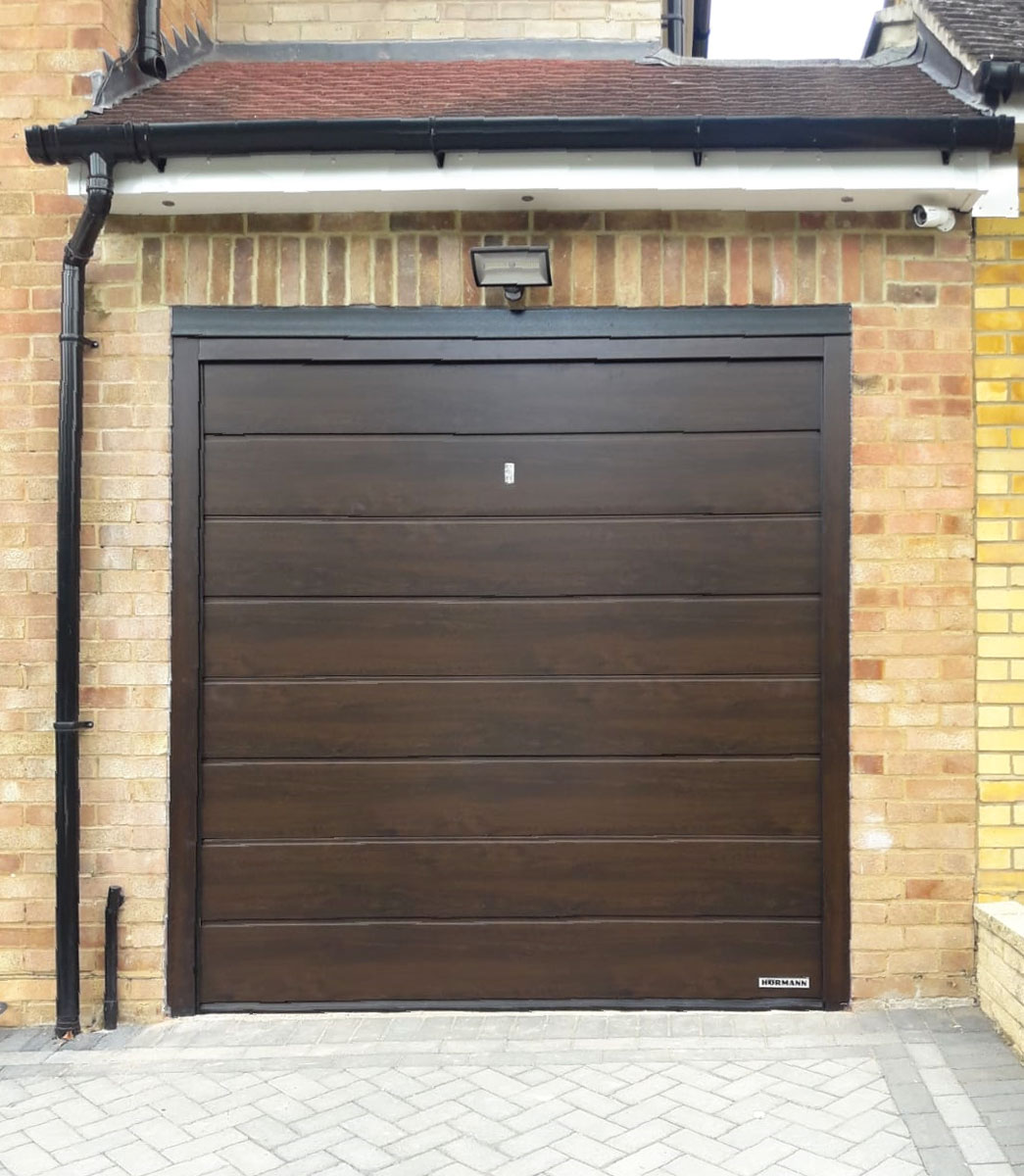 A Hormann LPU42 M Ribbed, Insulated Sectional Garage Door finished in a Dark Oak Decograin
