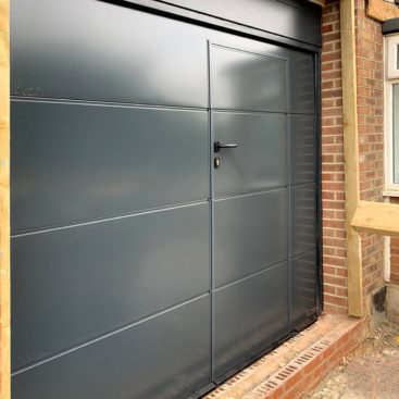 A Hormann LPU42 L-Ribbed Sectional Garage Door + Wicket Door finished in Anthracite Grey & Installed by our New Malden Branch.