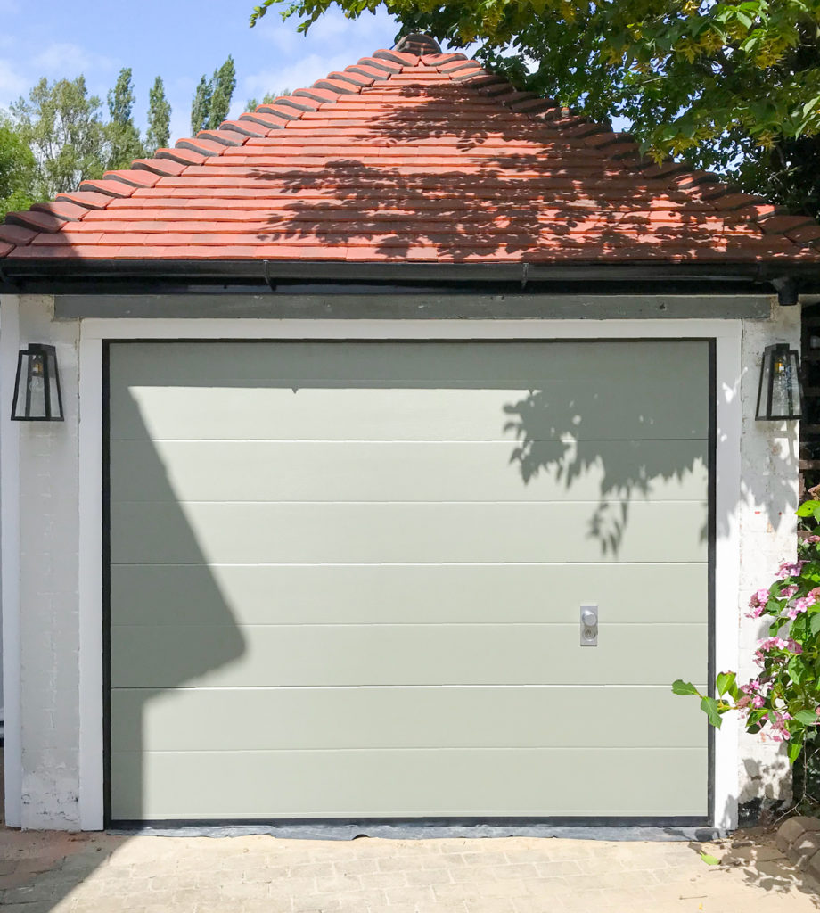 An SWS SeceuroGlide Elite Garage Door finished in Farrow & Ball Pigeon between the opening in a white frame. It features manual operation with an aluminium handle which was fitted by our Watford Branch in Middlesex.