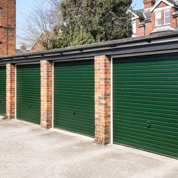 A row of four Garador Horizon Steel Retractable Up & Over Garage Doors in Moss Green