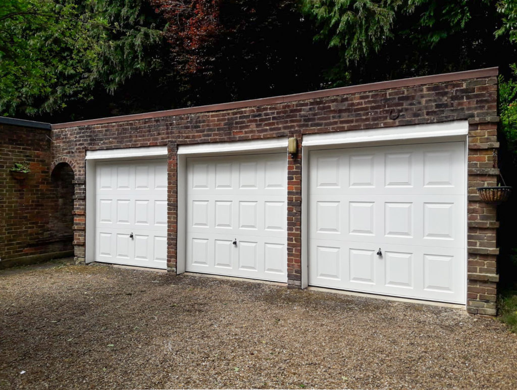 A trio of Garador Georgian up and over garage doors in white